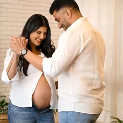 A joyful and candid maternity shot of a couple dancing together in the studio. Their smiles capture the happiness of this special journey.