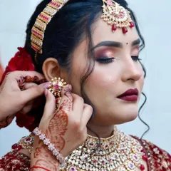 The final touches are what bring the entire bridal look together. Here, I'm placing the jewelry on my bride, whose makeup features a stunning cranberry smokey eye and a deep red lip.