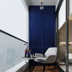 A small balcony transformed into a private coffee spot. The design features a comfortable chair, a small table, and a bold blue accent wall with louvered storage cabinets.