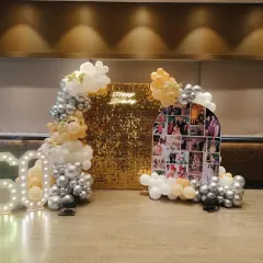 For this special 60th birthday, I designed a personalized backdrop featuring a collage of cherished family photos. The setup is complemented by a gold sequin wall, marquee light-up numbers, and an elegant balloon garland in white, silver, and peach tones.
