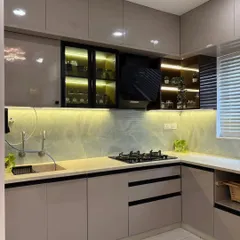 Another angle of the beige and white dual-tone kitchen, highlighting the L-shaped layout that provides an efficient work triangle. The under-cabinet lighting ensures the countertop is well-lit for food prep.