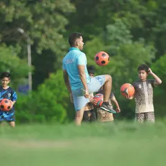 A coach demonstrates keep-up skills to a group of young, observant players. We lead by example to inspire our students.
