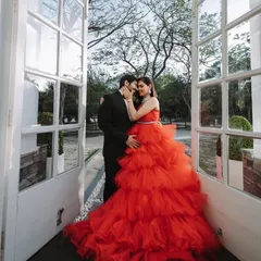 A beautiful shot of a couple framed by white doors, highlighting the volume and vibrant color of the red tulle gown. It’s a perfect example of how my dresses help create magazine-worthy photos.