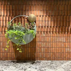 This is a piece from my Biophilic Art series, a custom wall planter against an exposed brick wall. The design symbolizes the dawn sky, with the brass element representing the sun and the green oasis depicting the earth, turning a simple wall into a story.