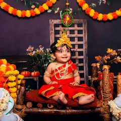This adorable baby Krishna is ready for the Janmashtami festivities. Our detailed setup includes everything from marigold garlands to pots of "makhan" to create an authentic scene.