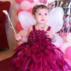 The birthday girl dressed as a beautiful fairy, holding a magic wand against a backdrop of pink balloons. A truly magical portrait.