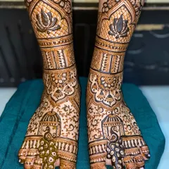 A close-up of bridal feet mehandi featuring beautiful peacock and lotus motifs. The fine line work and shading create a rich and detailed design.