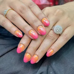 A full view of the stunning pink and orange ombre nails with a chrome finish. The colors blend seamlessly, creating a warm, tropical vibe that really pops.