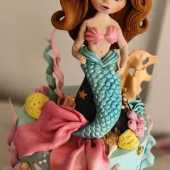 A close-up of the mermaid figurine I made for a first birthday cake. I sculpted her face, hair, and tail entirely by hand to look like a doll from a fairytale. These are the details that bring a themed cake to life.