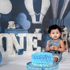 A cool blue theme for a little boy's first birthday cake smash. The hot air balloon backdrop and teddy bears create a dreamy and adventurous setting for his celebration.
