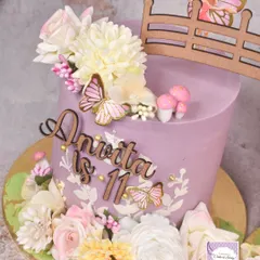 A close-up of one of the fairy garden cakes, adorned with flowers, butterflies, and a tiny fairy door.