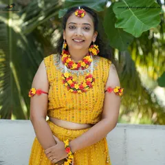 A lovely bridal portrait during her Haldi ceremony. The floral jewelry and yellow attire are beautifully complemented by the natural outdoor lighting, creating a fresh and vibrant image.