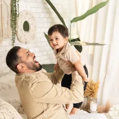 The pure joy of being lifted up by dad. This candid shot captures a moment of laughter and play during a relaxed, modern family session.