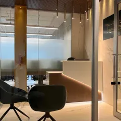 A view into the reception area of the advocate's office from the waiting lounge. The design uses a glass entryway to create a feeling of transparency and openness, while the modern seating offers comfort for visitors.