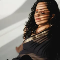 A close-up shot showing the subtle makeup for the black saree shoot. The focus is on a smooth skin finish, with soft brown eyeshadow and natural-looking lips, enhanced by the play of light and shadow.