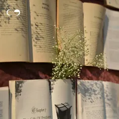 A close up of the book wall, where sprigs of baby's breath emerge from the pages of open books. This detail added a touch of delicate, whimsical beauty to the literary themed backdrop.