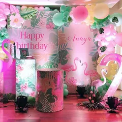 For a girl who loves flamingos, I designed this tropical-themed second birthday. The backdrop features lush leaves, paper flowers, and light-up flamingo props for a fun, vibrant glow.