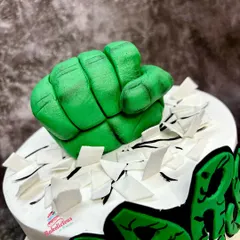 A close-up on the main event: the incredible Hulk fist, sculpted with detailed knuckles and muscles, looking like it's ready to punch through the cake.