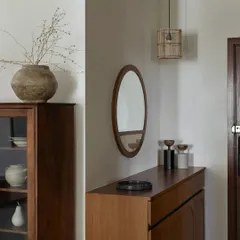 This foyer design is an example of Japandi principles: minimal, natural, and warm. A simple shoe unit and an oval mirror are complemented by wooden rafters on the ceiling. Nothing here overwhelms; instead, you are embraced by a sense of calm.