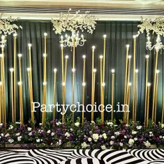 We designed this modern sangeet stage for a glamorous evening. The decor features a dramatic black backdrop, elegant chandeliers, and a series of vertical gold pillars with integrated lighting to create a sophisticated and high-energy ambiance.