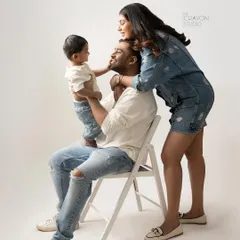 A mother's gentle touch and a father's steady presence create a beautiful frame for their child. This candid studio moment captures the loving dynamic of this young family.