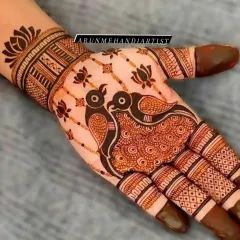 A simple yet striking design featuring two love birds as the centerpiece of the palm. The surrounding lotus motifs and patterned fingers complete this elegant piece of henna art.