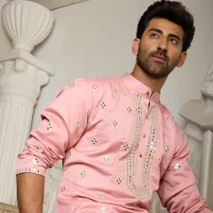 A blush pink kurta adorned with shimmering mirror work and delicate gold embroidery along the placket. This piece is the epitome of understated luxury, perfect for daytime celebrations.