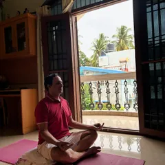 A client finds stillness and focus in Sukhasana (Easy Pose) during a guided meditation as part of his personalized home yoga plan.