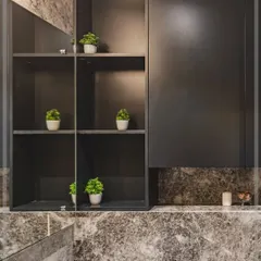A look at the overhead storage unit in the grey-toned bathroom. The combination of open and closed shelving, along with a large mirror, makes the space feel larger and more organized.