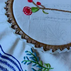 A work-in-progress shot of a floral hoop art design. You can see the pencil outline on the fabric, which I gradually bring to life with different colored threads and stitches.