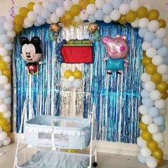 A closer look at the cradle setup for a themed naming ceremony. The blue and gold balloon arch creates a festive frame around the 'palna', where the baby will be placed for the ceremony.