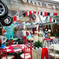 I create a complete race day atmosphere with checkered flag bunting, hanging tires, and themed tables. This overhead view shows how every element works together in a large tented space.