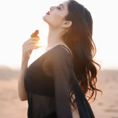A sensual and serene portrait of a model in a sheer black outfit against the setting sun. The backlighting and the prop rose add a touch of romance and mystery.