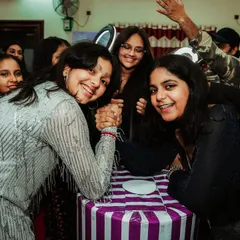 Friends sharing a moment of fun and friendly competition with an arm-wrestling match at a Taylor Swift themed party.