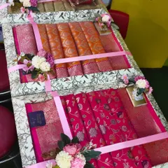 I can pack multiple sarees together in large trays like this one. Here, I have arranged beautiful Banarasi sarees with floral decorations for a wedding gift.