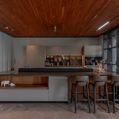 For this Ahmedabad home, we created a kitchen with architectural clarity. The handleless cabinetry in Porto Matt Lacquer provides a sleek, uninterrupted flow, while the layered island combines tactile wood shelving with bold, shadow-toned counters for a modern, sophisticated look.
