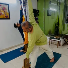 Props help us find the correct alignment. Here, students use wall ropes and blocks in Utthita Trikonasana (Extended Triangle Pose) to open the chest and lengthen the spine without strain.