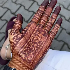 A groom's mehndi, showing the rich, dark stain on his palm. The design is a traditional pattern, perfect for wedding ceremonies.