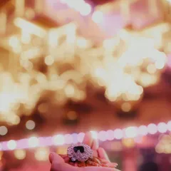 A creative detail shot focusing on the groom's brooch, with the beautiful bokeh of the event lights in the background. It’s the little things that set the mood.