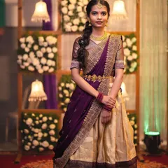 A full-length shot of the sister of the bride. Her makeup is subtle, ensuring it complements her traditional half-saree without overpowering it. She looks elegant and ready for the wedding.