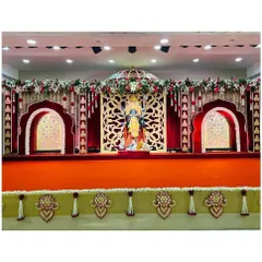 The main stage for a Kali Puja celebration at Hiravati Banquet Hall. The design features a traditional red and gold color scheme, with ornate jharokha-style arches and a rich red velvet backdrop for the deity.