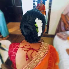 A traditional low bun, or juda, adorned with a simple line of white flowers. This is a timeless and graceful hairstyle for wearing with a saree.