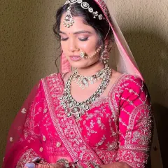 A close-up of a beautiful bride in her pink lehenga, looking down with a gentle smile. Her heavy kundan set, including the matha patti and nath, was the perfect choice for her grand celebration.