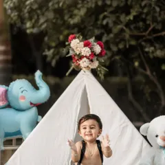 The moment of pure excitement just before the cake smash begins. I love capturing the anticipation in this outdoor teepee setup, complete with balloons and a special birthday cake.