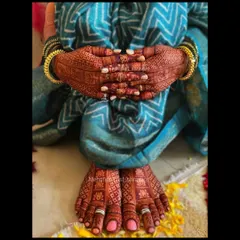A stunning view of matching hand and foot mehendi. The feet are covered in a dense geometric pattern with lotus details, perfectly complementing the bride's attire.