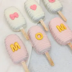 Our "MOM" cakesicles, decorated in pink and white chocolate, are a cute and delicious part of our Mother's Day hamper.