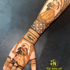 I love creating both modern and traditional looks. This design features a romantic couple on a swing on the palm, complemented by a contemporary portrait on the forearm, showing how we can blend different styles for a full bridal look.