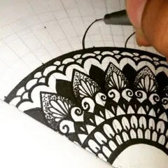 My hand at work, filling in the patterns of a semi-mandala. You can see the underlying grid I use to guide the drawing. This step-by-step process is what makes creating complex designs manageable for beginners.