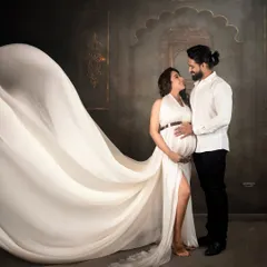 A beautiful moment between partners. I love capturing these intimate connections, with the flowing white gown adding a touch of elegance and drama to this maternity couple portrait against a classic studio backdrop.
