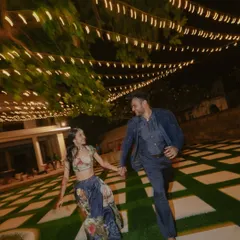 A candid shot of a couple running barefoot and laughing under a canopy of fairy lights in Kenya. This image is full of joy, movement, and the magic of a warm evening celebration.